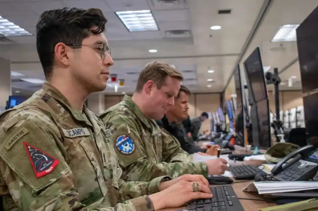 Service members collaborating on mission support operations at computer workstations.